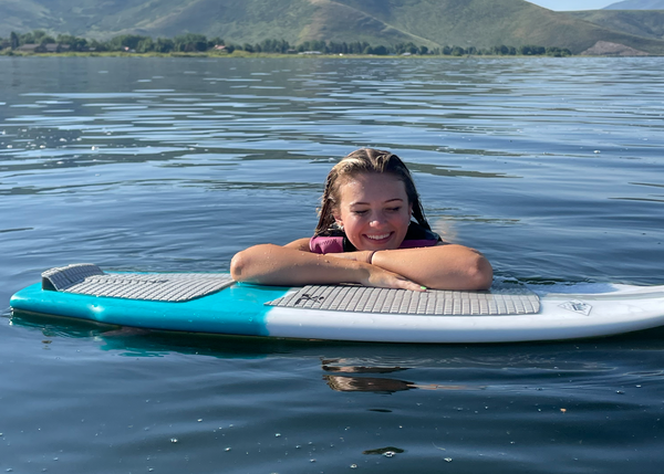 Girl in the water resting arms on Grubby Hobie Wakesurf Board